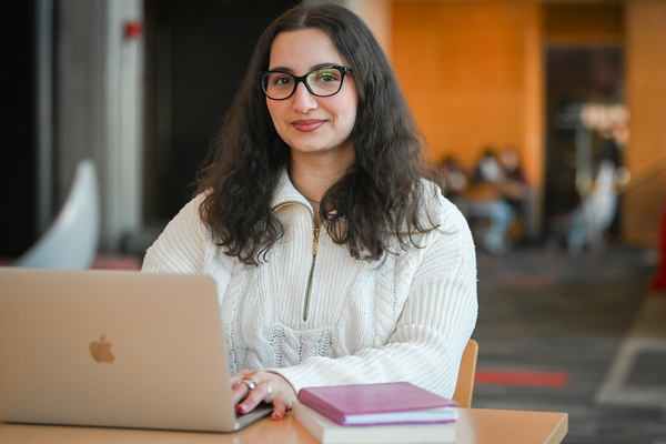 Sara Parvin sits at table with laptop open