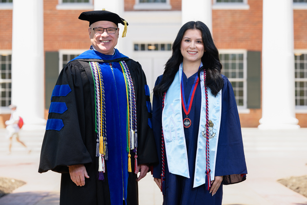 Image of Provost Noel Wilkin and banner bearer Katherine Lydia Tibbs in graduation regalia.