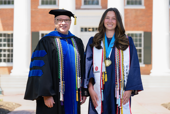 Image of Provost Noel Wilkin and banner bearer Grace Allagene Landry in graduation regalia.