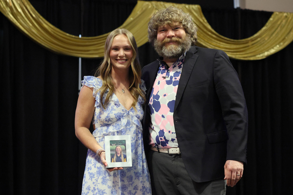 Student poses with plaque next to staff member