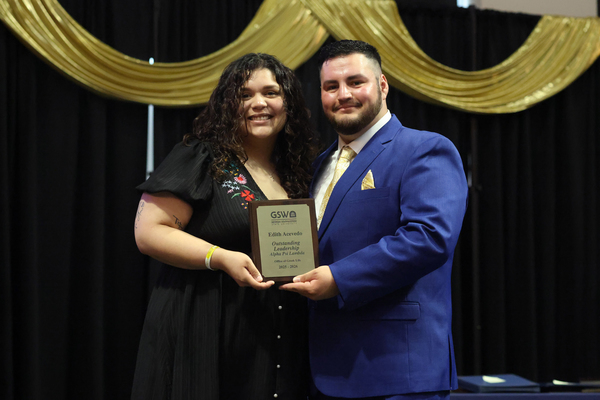 Student poses with plaque next to staff member