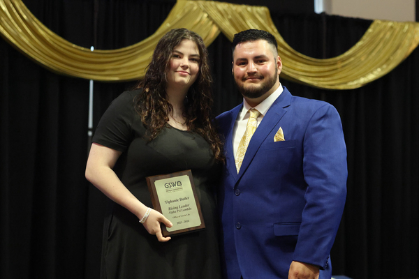 Student poses with plaque next to staff member
