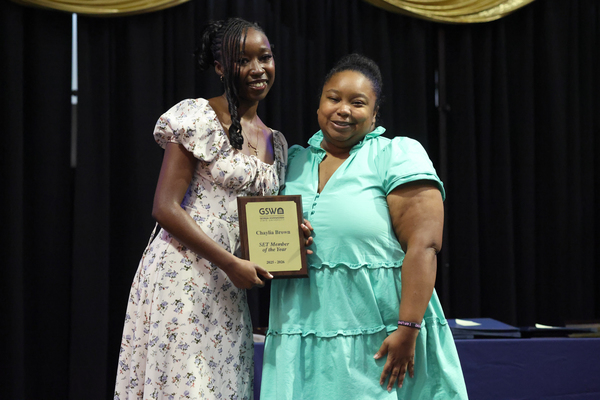 Student poses with plaque next to staff member
