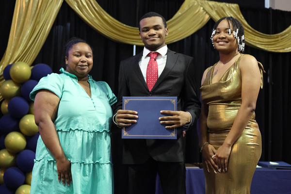 Student poses with plaque next to staff member
