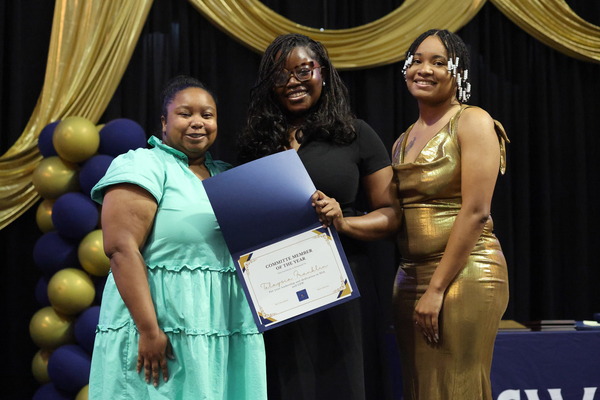 Student poses with plaque next to staff member