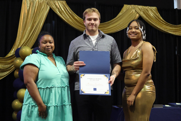 Student poses with plaque next to staff member