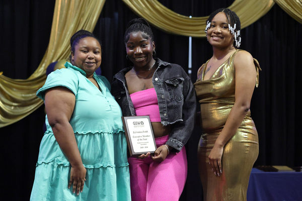 Student poses with plaque next to staff member