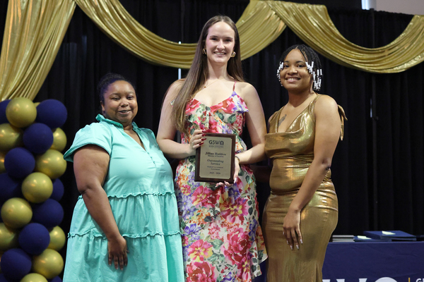 Student poses with plaque next to staff member