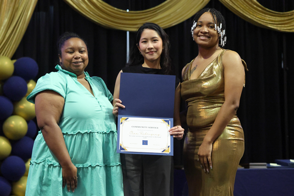 Student poses with plaque next to staff member
