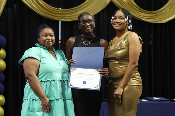 Student poses with plaque next to staff member