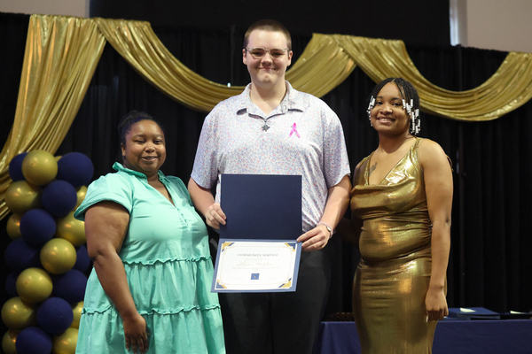 Student poses with plaque next to staff member