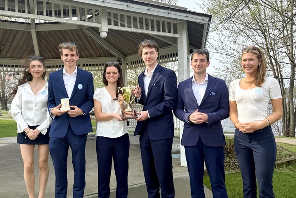 Students in business attire pose with their trophy in Ives Park in downtown Potsdam.