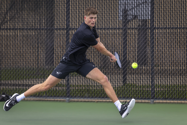 A college tennis player hitting a backhand shot.