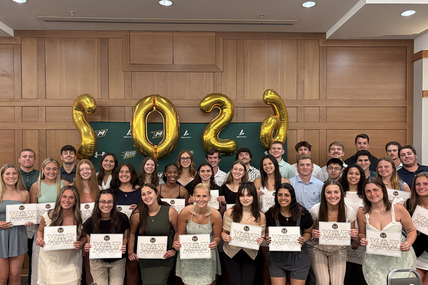 Students standing in a group holding their induction certificates and smiling for a photo