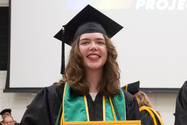 Student with graduation cap and gown on smiling for a picture. 