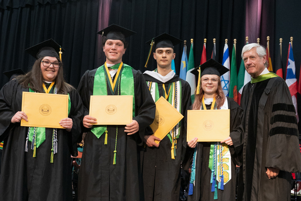 Winners of the Argonaut Award holding their certificates and smiling for a picture in their cap and gown