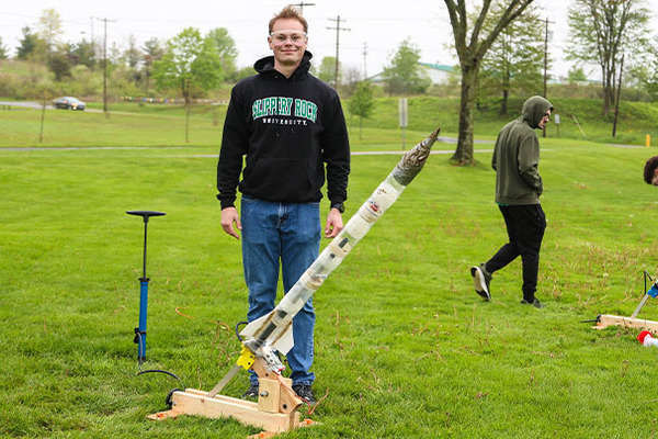 Student standing with rocket.