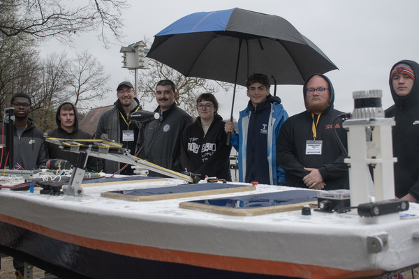 Students standing behind low-profile vessel