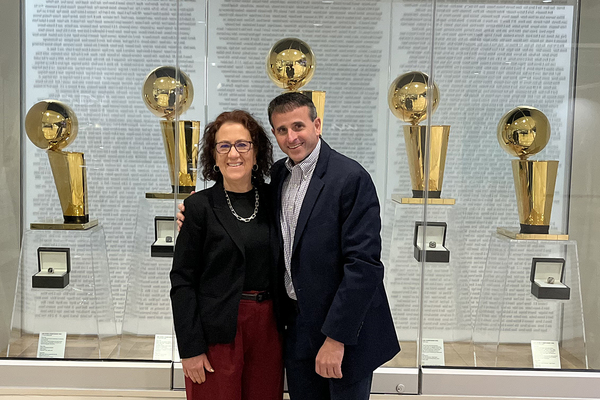 GONNA NEED A BIGGER TROPHY CASE? Monmouth President Patricia Draves is pictured with Tim Salier '96 in front of the five NBA championships trophies that San Antonio has won. Salier has been with the organization for four of them.