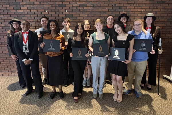 Current members of Kettering University's Robot Society and student honorees pose for a group photo in front of a brick wall.