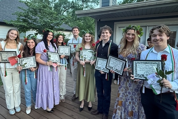 students stand on a deck holding certificates at the initiation ceremony