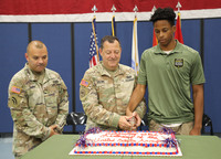 Cake cutting ceremony with two Soldiers in uniform and a recruit.