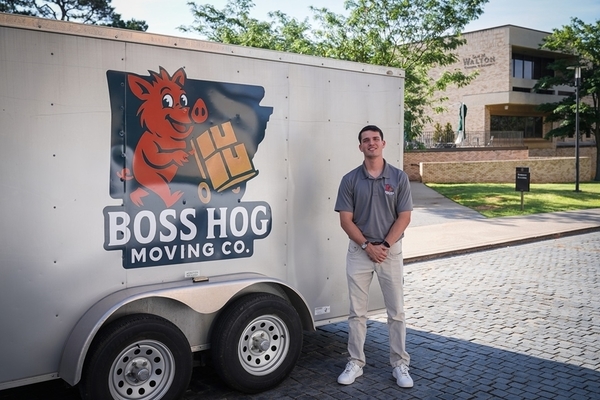 student stands in front of his moving trailer