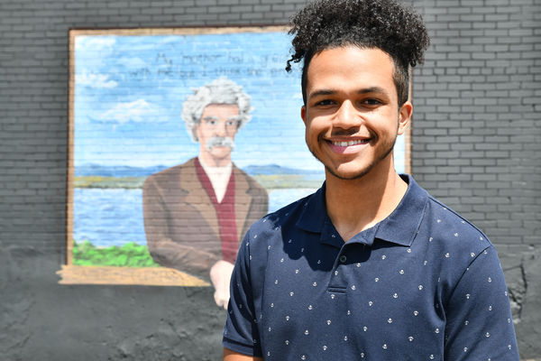 Lindsey Wilson University student Tezon Mitchell ’27 of Greensburg, Kentucky, stands next to the Mark Twain mural he painted on a Columbia building on Jamestown Street. The mural was dedicated on Monday, June 15, to celebrate and preview the upcoming “Mark Twain Storytelling Festival,” which will be held June 19-20 at Lindsey Wilson.