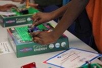 A young boy shows how a simple generator was made with a kit. The box the kit came in says "Green Energy."