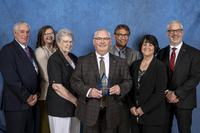 Employees of SeaComm Federal Credit Union stand in front of a blue backdrop at the SUNY Canton Hall of Fame ceremony. 