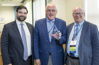 Geoffrey VanderWoude, Carl Trainor, and SUNY Canton President Zvi Szafran stand together while Trainor holds a hall of fame trophy. 