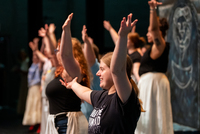A group of performers hold out their arms during a dance in the production of "Cinderella," with one performer smiling in the foreground.
