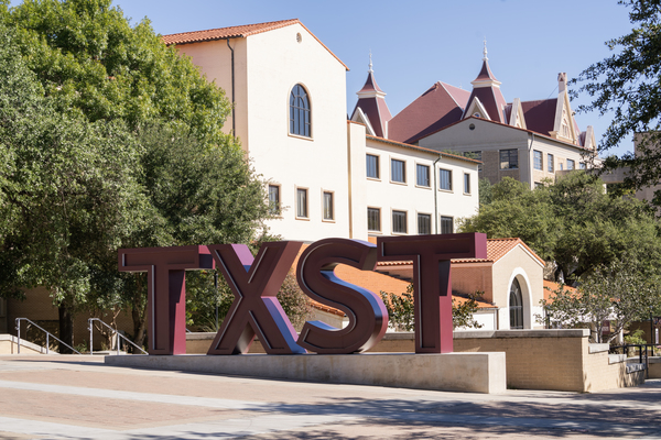 TXST sculpture in front of historic campus building. 