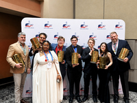 SUNY Delhi's culinary hot food competition team poses with trophies in front of a backdrop, dressed in formal wear.