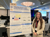 Student standing to the right of research poster