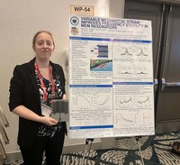 Student holding device and standing to left of research poster