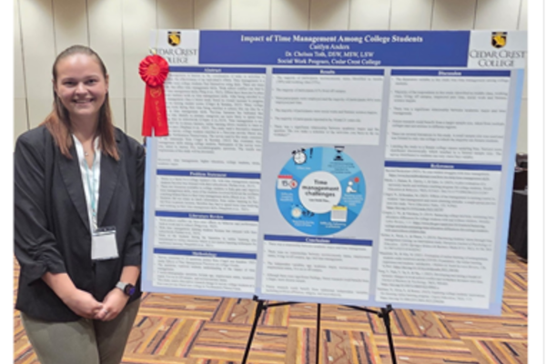 Caitlyn Anders standing beside with her poster presentation.