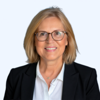 Woman with blond hair and classes wearing white collared shirt and black jacket.