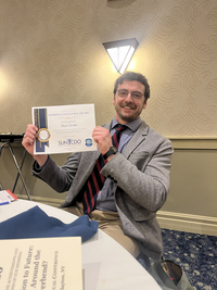 Max Grube holds up an award certificate at the SUNY CDO conference.