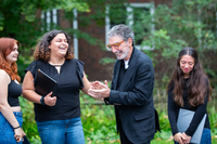 Chuck Lorre claps while visiting the SUNY Potsdam campus. Students are laughing and talking to him.