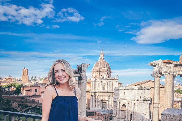 Emma Hurley, wearing a navy blue sundress, is pictured against the backdrop of Rome.