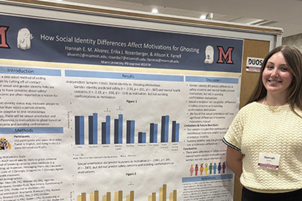female standing in front of large poster displaying research