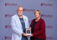 Stephan Savoia accepts the Minerva Award from SUNY Potsdam President Suzanne Smith.