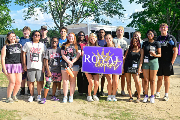 A group of students gathered together during IMPACT orientation, smiling and posing for a group photo in a welcoming campus setting. 