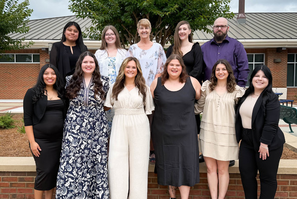 Eleven Vet Tech graduates pose for a photo outside a brick building
