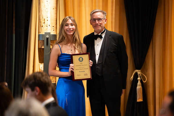 Allison McGraw holding her Outstanding Thesis Award, alongside University President Dr. Robert K. McMahan.
