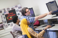Rob Hinckley reaches over a student's shoulder to point at a computer screen she is working on during a politics class at SUNY Potsdam.