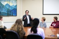 Rob Hinckley leads a lecture on campus, with students surrounding a large table listening in.