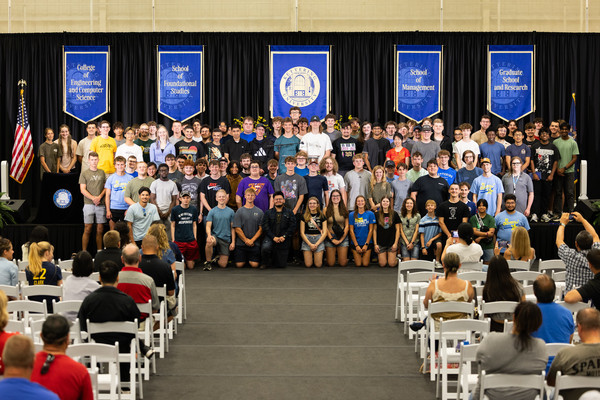 A-Section Class of 2030 students pose for a group photo on stage during Convocation at Kettering University as family and guests look on.