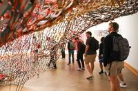 Students in an art exhibit with netting and fibers